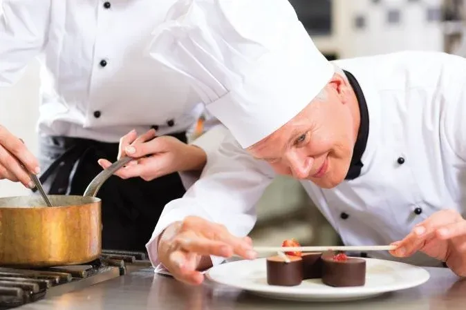 chef en train de dresser des desserts avec soin dans une cuisine professionnelle