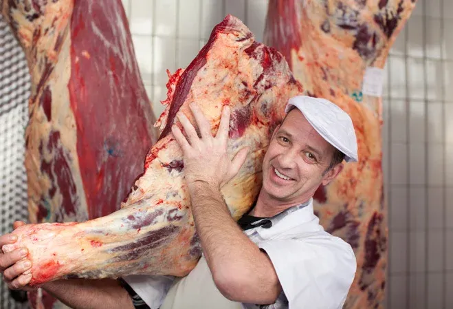 Risque TMS porte des charges lourdes : un boucher qui soulève de la viande sur son dos