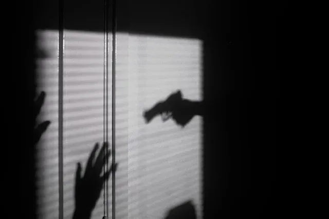 ombres de mains et d'une arme projetées sur un mur avec des rayures de lumière