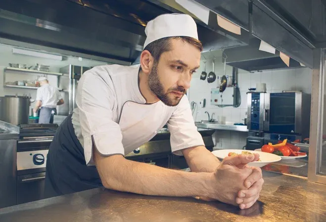 Chef cuisinier déprimée et soucieux croise les mains sur la table de son restaurant