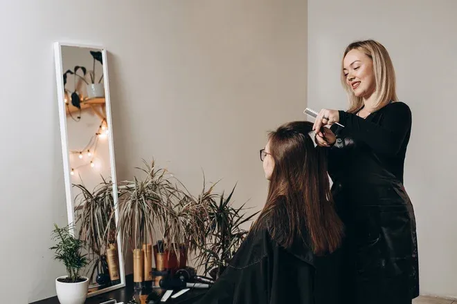 coiffeuse coupant les cheveux d'une cliente devant un miroir